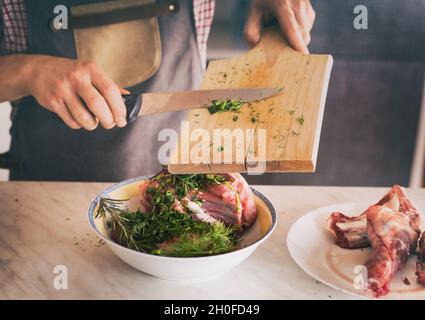 Nahaufnahme der männlichen Hände, die Gewürze auf frisches Fleisch legen. Kochkonzept zu Hause Stockfoto