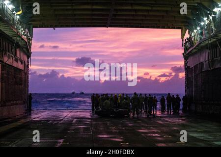 US-Marineinfanteristen mit der 31. Marine Expeditionary Unit (MEU) und Matrosen der Marine bereiten sich darauf vor, während einer Onload-Übung an Bord des Landungsschiffes USS Ashland (LSD 48) in der philippinischen See, 24. Februar 2021, ein Kampfflugzeugnis zu Bergen. Die 31. MEU ist an Bord der Schiffe der Amphibiengeschwader 11 im Einsatzgebiet der 7. Flotte tätig, um die Interoperabilität mit Verbündeten und Partnern zu verbessern und als einsatzbereite Einsatztruppe zur Verteidigung von Frieden und Stabilität in der Indopazifik-Region zu dienen. Stockfoto