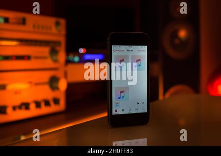 Smartphone als Fernbedienung für Home Sound System. Farbenfroher Hintergrund mit Lautsprechern und Verstärker Stockfoto