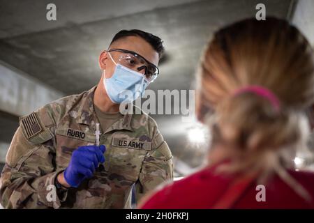 SPC der US-Armee. Christian Rubio von Phoenix, Arizona, einem Kampfmediziner, der dem Hauptquartier und Hauptquartier Battery, dem 2. Bataillon, dem 12. Artillerieregiment, dem 1. Stryker Brigade Combat Team, der 4. Infanterie-Division, zugewiesen ist, beantwortet Fragen eines lokalen Gemeindemitglieds über den COVID-Impfstoff im California State University Los Angeles Community Impfinction Center, 26. Februar 2021. Rubio geimpfte Menschen bei der CVC im Cal State LA. Das U.S. Northern Command setzt sich über die U.S. Army North weiterhin dafür ein, der Federal Emergency Management Agency A weiterhin flexible Unterstützung durch das Verteidigungsministerium zu leisten Stockfoto