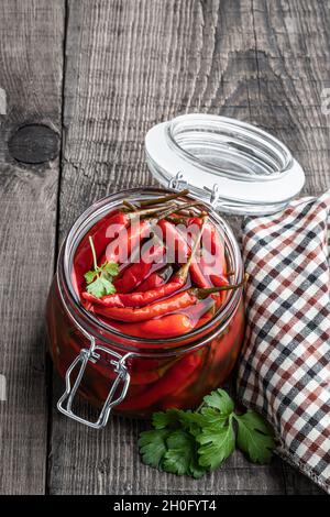 Rot würziger marinierter Pfeffer in Holzschüssel auf dem rustikalen Tisch Stockfoto