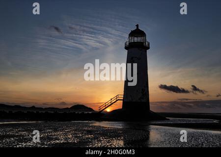 Die Sonne geht hinter den Dünen gegen den Punkt des Ayr Lighthouse auf Talacre, Nordwales, unter. Stockfoto