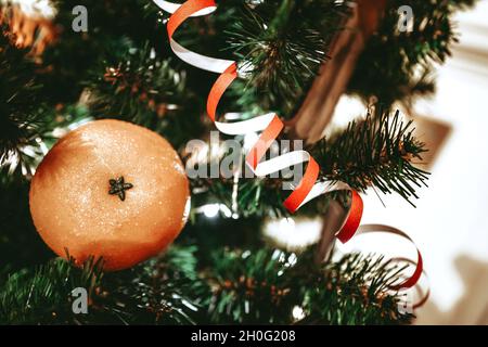 Mandarine und Serpentin auf dem Weihnachtsbaum. Komposition zum neuen Jahr. Weihnachtsbaum Äste. Stillleben zu Weihnachten. Stockfoto