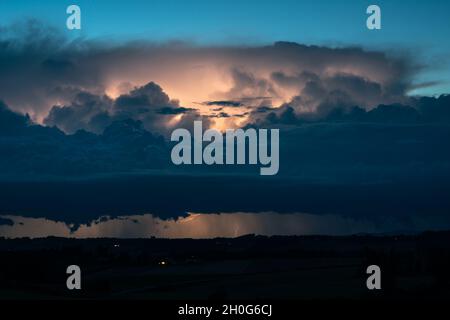 Dramatisch aussehender Gewitter an der Grenze zwischen Österreich und Deutschland während der Blauen Stunde Stockfoto