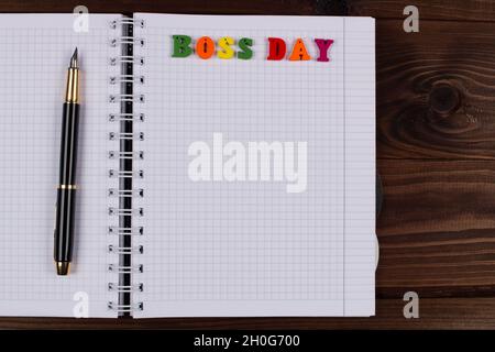 National Happy Boss Day. Bunte Buchstaben in einem karierten Übungsbuch mit Stift auf dem Tisch. Boss's Day Office Grußkarte mit Kopie Spa Stockfoto