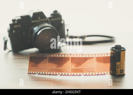 Negativer Filmstreifen aus der Filmrolle mit Vintage-Filmkamera im Hintergrund Stockfoto