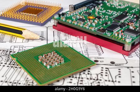 Platine, Stift und Prozessoren auf dem Hintergrund des Schaltplans und einer Fotomask für die Herstellung von Leiterplatten. Stockfoto