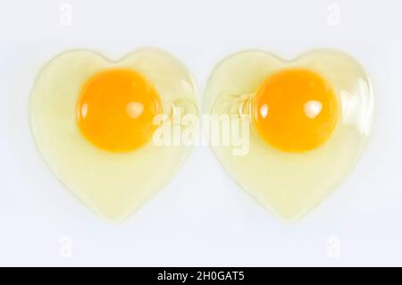 Rohe zerrissene Eier nebeneinander in Herzform auf weißem Hintergrund Stockfoto