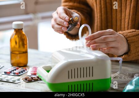 Frau, die ätherisches Öl in den Vernebler auf den Tisch gegeben hat Stockfoto