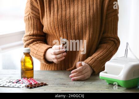 Frau mit einer Flasche ätherisches Öl und Vernebler auf dem Tisch Stockfoto