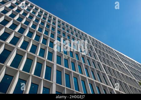 Modernes, mehrstöckiges Bürogebäude oder Wohnblock, abstraktes Bild der Etagen und Ebenen des Gebäudes. Abstraktes Bürogebäude. Abstrakte Architektur Stockfoto