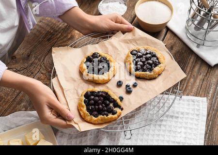 Frau hält Gitter mit leckeren Heidelbeer-Galettes in der Küche Stockfoto