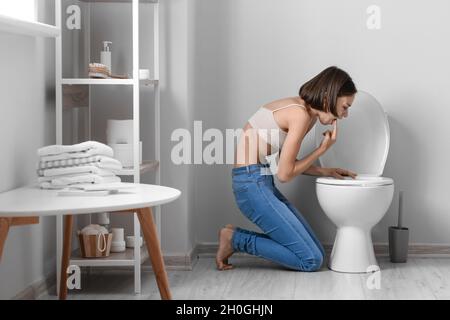 Junge Frau in der Nähe von Toilettenschüssel im Badezimmer. Anorexie-Konzept Stockfoto