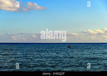 Ein kleines Schlauchboot mit einem Schiffbrüchigen, der mitten im Meer verloren ging Stockfoto