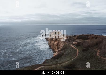 Große Wellen von Nazare und Fort von Sao Miguel Arcanjo an einem bewölkten Tag - Nazare, Portugal Stockfoto