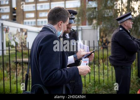 London, Großbritannien. Oktober 2021. Ein Mitglied der Öffentlichkeit erkundigt sich bei der Polizei nach Einzelheiten des Falles.Eine Mahnwache wurde von der örtlichen Gemeinde Tower Hamlets zum Gedenken an Ranjith Kankanamalage abgehalten, der im August in East London von einem homophoben Mörder getötet wurde. Die Met-Polizei stellte sich bei der Mahnwache vor und verteilte Flugblätter, um die Öffentlichkeit zu bitten, sich zu melden, wenn sie irgendwelche Informationen über den Vorfall haben. Kredit: SOPA Images Limited/Alamy Live Nachrichten Stockfoto