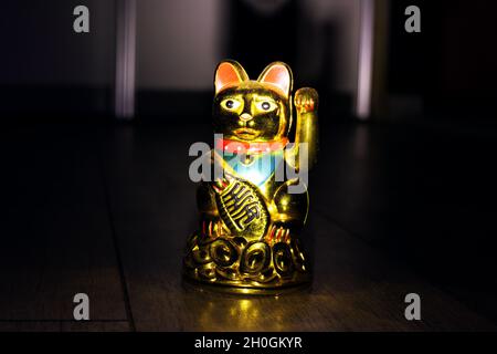 Japanische Katze maneki neko im Dunkeln Nahaufnahme Stockfoto