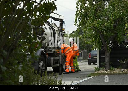 Straßenwartung. Diese Männer räumen einen Abfluss an der Bordsteinwand in einer Wohnstraße, um sicherzustellen, dass die Straße in Wickford, Essex, frei von Oberflächenwasser ist. Stockfoto