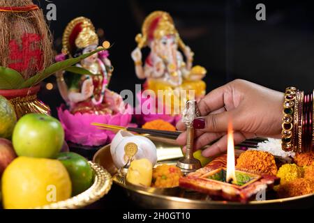 Hände Des Mädchens, Das Ghanti Bell Hält. Clay Diya Deep Dia Lampe Beleuchtet In Pooja Thali Für Aarti Von Maa Lakshmi & Bhagwan Ganesh Deva. Diwali Puja , Ne Stockfoto