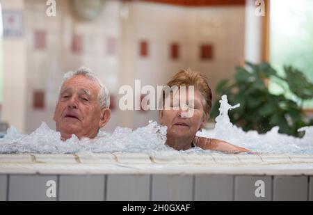 Ein älteres Paar genießt das Hallenbad mit heißem Wasser im Spa-Resort Stockfoto