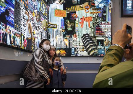 Hongkong, China. Okt. 2021. Die Besucher posieren für ein Bild vor dem Kunstwerk mit dem Titel ''Collected Memories'' von Derry Ainsworth auf der Digital Art Fair Asia in Hongkong, China, am 08. Oktober 2021. Die Messe zeigt NFT Crypto Art, nicht-fungible Token, als Teil des neuen Trends in der modernen Kunst. (Bild: © Miguel Candela/SOPA Images via ZUMA Press Wire) Stockfoto