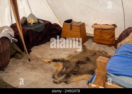 Eine Nachbildung eines wikingerzeltes mit Tierpelz auf dem Boden und Lifestyle-Objekten, darunter ein Mesh-Helm-Objekte in einer Nachstellung Truppe Dorfmesse Stockfoto