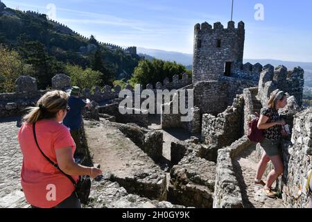 Sintra, Portugal. Okt. 2021. Die Menschen gehen durch die Befestigungslinie und die Türme innerhalb der Einrichtungen von Castelos dos Mouros.die maurische Burg, die von der UNESCO zum Weltkulturerbe erklärt wurde, verdankt ihren Namen der Vergangenheit der muslimischen Besatzung Portugals, Dient für seine optimale Lage an der Spitze als strategische Position Punkt mit einem vollen Blick auf die Umgebung. Die maurische Burg wurde 1154 von den Christen erobert. Im 19. Jahrhundert ordnete König Fernando II. Von Portugal seine Rekonstruktion an, um sie in die Gärten des Pena-Palastes zu integrieren und den Orel zu erholen Stockfoto