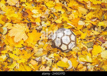 Alte Fußball auf herbstlichen Blättern liegend, herbstlicher Hintergrund Stockfoto