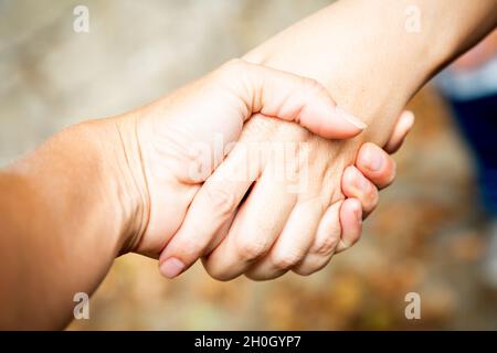 Diagonale Komposition. Zwei Hände zittern im Freien. Teamarbeit und Vereinbarung. Solidarität und Unterstützung von Frauen. Kaukasische Palme. Stärke und Stockfoto