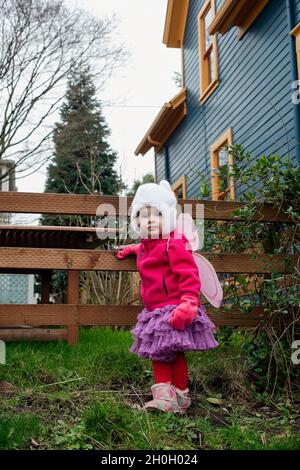 Ein kleines Mädchen, das sich dazu entschieden hat, ihre Feenflügel als ihr tägliches Outfit zu hören. Stockfoto