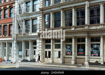 Ein Mann, der die Broome Street im SOHO-Viertel von New York City entlang läuft. Die leeren Ladenfronten haben für Leasing-Zeichen. Stockfoto