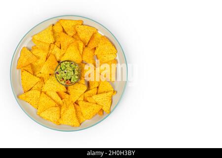 Eine große Platte mit knusprigen Nacho- und Guacamole-Chips in der Mitte der Schale auf einer weißen Platte mit Platz für Text. Draufsicht. Stockfoto