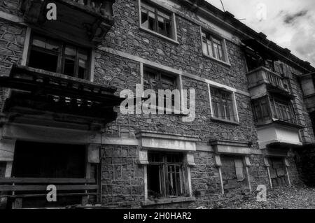 Schwarz-Weiß-Foto von alten verlassenen teilweise eingestürzten Gebäude mit komplizierten Mauerwerk, zerstörten Balkonen, zerstürzten Fenstern. Desolation und Stockfoto