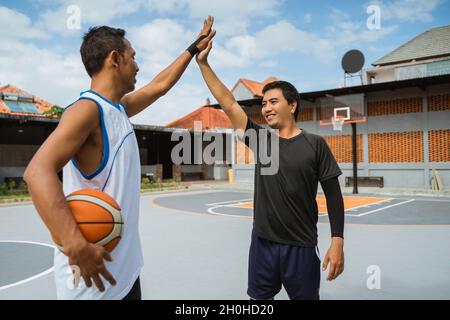 Zwei männliche Basketballspieler mit hohen Fünfen in der Pause spielen Basketball Stockfoto