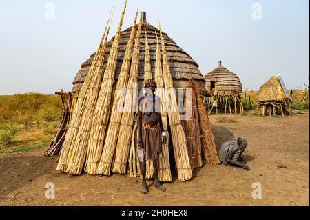 Frau vor ihrer Hütte mit vorbereitetem Schilf, Jiye-Stamm, Staat Eastern Equatoria, Südsudan Stockfoto