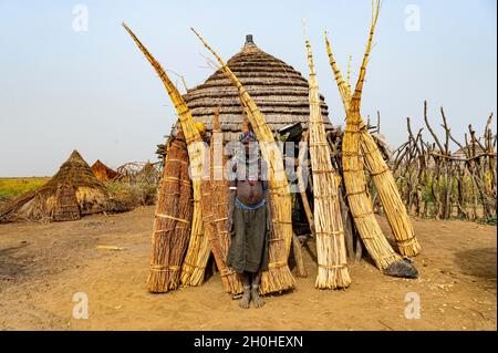 Frau vor ihrer Hütte mit vorbereitetem Schilf, Jiye-Stamm, Staat Eastern Equatoria, Südsudan Stockfoto