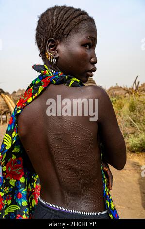 Narbe Gesicht und Körper als Zeichen der Schönheit Frau aus dem Stamm der Jiye sitzt in ihrer Hütte, Eastern Equatoria State, Südsudan Stockfoto