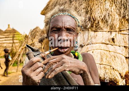 Alte Frau des Jiye-Stammes, die eine Pfeife raucht, Eastern Equatoria State, Südsudan Stockfoto