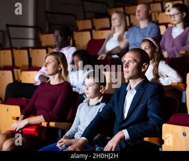 Eine Familie von Theaterbesuchern mit einem Sohn aus dem Jugendalter, der sich eine Theateraufführung ansieht Stockfoto