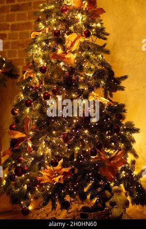Weihnachtsbaum mit festlichen Dekorationen in warmer Wohneinrichtung. Stockfoto