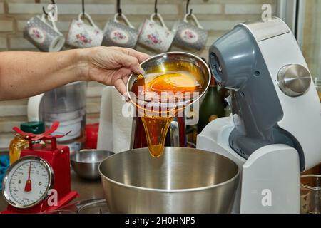 Der Koch gießt Honig aus der Waage in den Salat. Schritt für Schritt Rezept Stockfoto