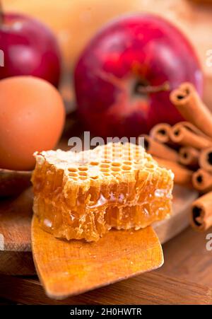 Honiglöffel, Glas Honig, Äpfel und Zimt auf einem Holzhintergrund in einem rustikalen Stil. Stockfoto