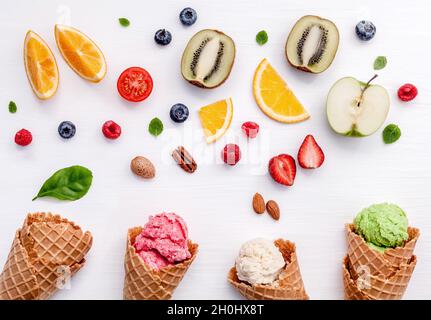 Kegel und bunten verschiedene Früchte Himbeere, Heidelbeere, Erdbeere, Orange Slice, halbe Kiwi, Apfel, Tomate und Pfefferminze Blätter setup auf weißen backgr Stockfoto