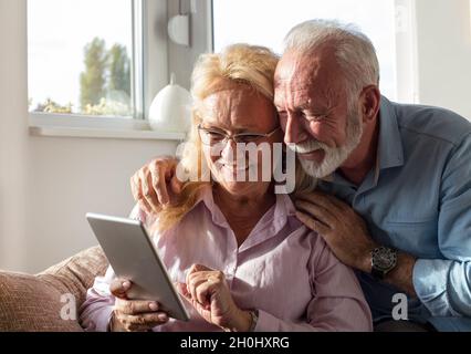 Ein älteres Paar, das ein Tablet für die Kommunikation mit der Familie verwendet Stockfoto