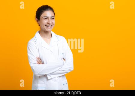 Porträt der indischen Ärztin in weißem medizinischen Kleid isoliert auf gelbem Hintergrund. Stockfoto