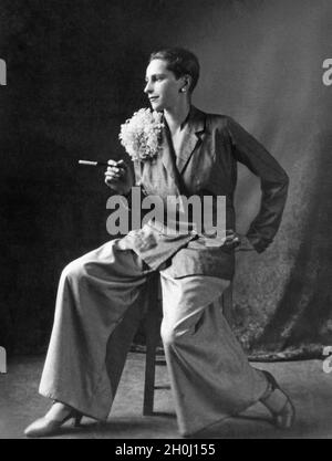 Ein Frauenmodel in den 1920er Jahren trägt einen von Herrenmode inspirierten Anzug und raucht eine Zigarette. [Automatisierte Übersetzung] Stockfoto
