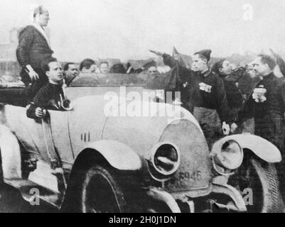 „Benito Mussolini, der im Oktober 1922 in einem Auto stand, hält eine Rede an seine Anhänger, die ihn mit dem „Saluto romano“ begrüßen. Ende Oktober fand der ''Marsch gegen Rom'' statt, der die italienischen Faschisten an die Regierung brachte. [Automatisierte Übersetzung]' Stockfoto