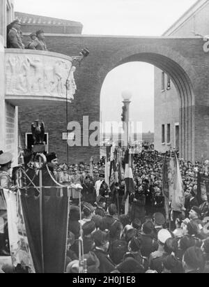 Am 29. Oktober 1937 weihte Benito Mussolini (links, auf dem Balkon) die Aprilia-Siedlung in den Pontinischen Sümpfen ein, die im April neu gegründet und zuvor entwässert wurde. Reichsminister Rudolf Hess war bei seiner Rede (links) anwesend. Der Balkon ist Teil des Torre Littoria auf der Piazza Roma. [Automatisierte Übersetzung] Stockfoto