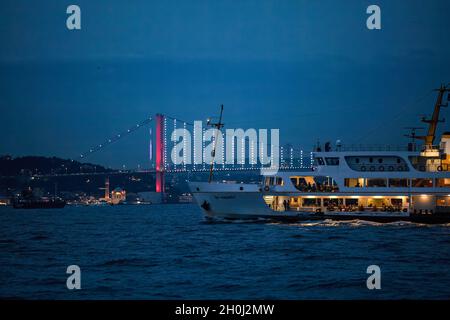 Istanbul, Türkei. Oktober 2021. Die City Lines Fähre fährt durch den Bosporus zur blauen Stunde zusammen mit der Martyrs-Brücke vom 15. Juli, bei bewölktem Wetter am Abend vor dem Regen um Eminonu nach Kadikoy. Kredit: SOPA Images Limited/Alamy Live Nachrichten Stockfoto