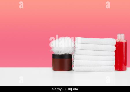 Stapel Handtücher, Flaschen mit Shampoo auf weißem Tisch Stockfoto